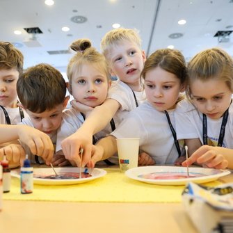 Grupa dzieci nad stołem, na którym widać różne barwniki